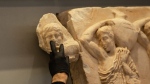 An Acropolis Museum staff places a male head on the frieze of the Acropolis museum during a ceremony for the repatriation of three sculpture fragments, in Athens, on Friday, March 24, 2023. (AP Photo/Petros Giannakouris)