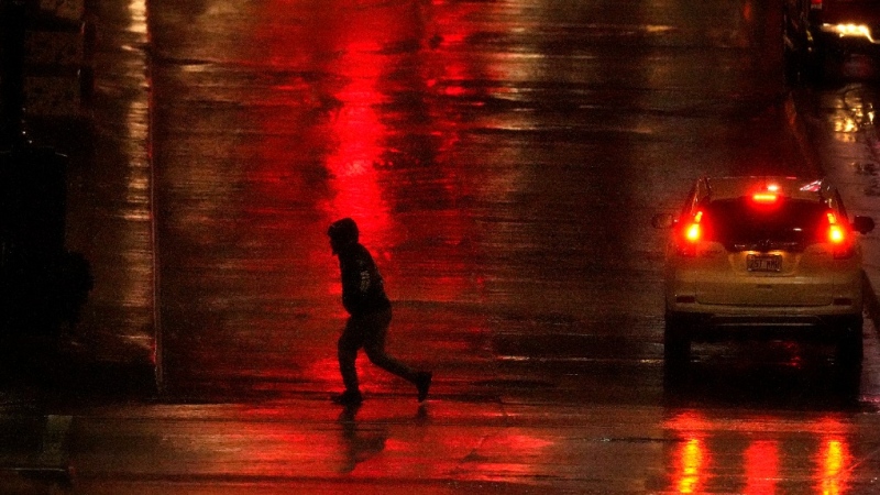 In this file photo, a man crosses a rain-slick street in downtown Kansas City, Mo., as a thunderstorm passed through the area, late Monday, Jan. 2, 2023. (AP Photo/Charlie Riedel)