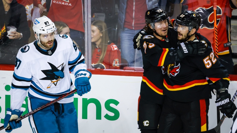 San Jose Sharks forward Martin Kaut, left, skates away as Calgary Flames forward Tyler Toffoli, centre, celebrates his goal with teammate defenceman MacKenzie Weegar during first period NHL hockey action in Calgary, Alta., Saturday, March 25, 2023.THE CANADIAN PRESS/Jeff McIntosh