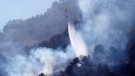 A helicopter with a bucket of water drops water to extinguish the forest fire in Montanejos, Castellon de la Plana, Spain, Sunday March 26, 2023. (AP Photo/Alberto Saiz)