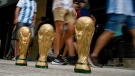 Soccer fans walk past replicas of the FIFA World Cup trophy outside the Monumental stadium prior to an international friendly soccer match between Argentina and Panama in Buenos Aires, Argentina, Thursday, March 23, 2023. (AP Photo/Rodrigo Abd)