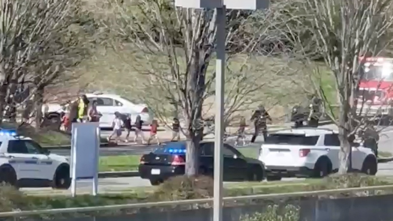 In this image from video provided by Jozen Reodica, law enforcement officers lead children away from the scene of a shooting at The Covenant School, a private Christian school in Nashville, Tenn., on Monday March 27, 2023. (Jozen Reodica via AP)