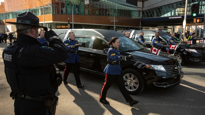 A sheriff salutes during the procession for Edmonton Police Service constables Travis Jordan and Brett Ryan in Edmonton, Monday, March 27, 2023. The officers were killed in the line of duty on March 16, 2023. THE CANADIAN PRESS/Jason Franson