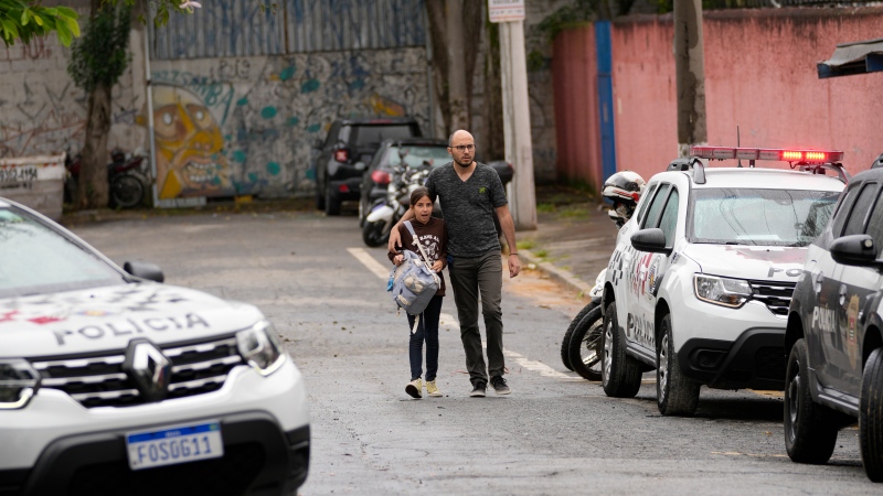 A student leaves the Thomazia Montoro school with her father after a fatal stabbing at the school in Sao Paulo, Brazil, Monday, March 27, 2023. (AP Photo/Andre Penner)