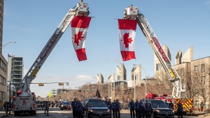 Firefighters deploy flags during the procession for Edmonton Police Service constables Travis Jordan and Brett Ryan in Edmonton, Monday, March 27, 2023. The officers were killed in the line of duty on March 16, 2023 (The Canadian Press/Jason Franson).