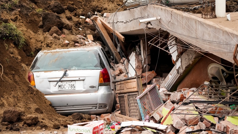 A car is covered by the debris of a collapsed house after a deadly landslide caused by heavy rains buried dozens of homes in Alausi, Ecuador, Monday, March 27, 2023. (AP Photo/Dolores Ochoa)