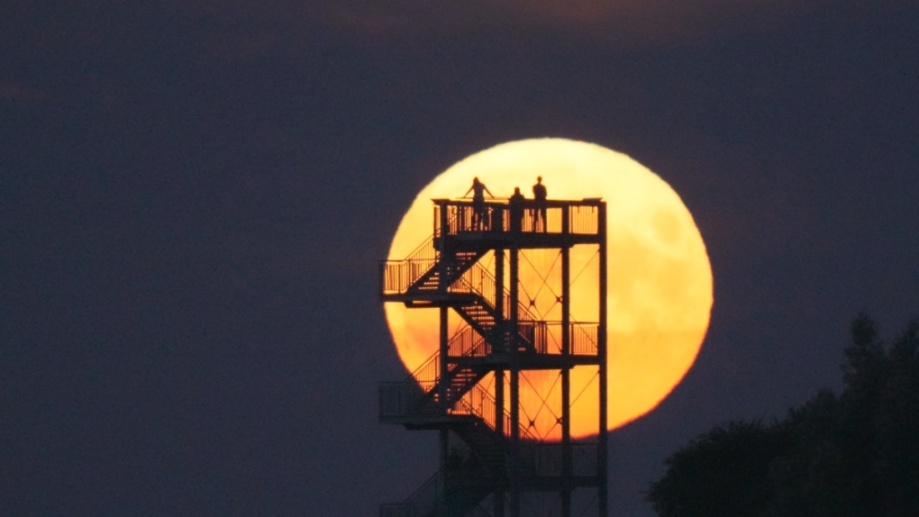 People watch the moon rise in July, 2022