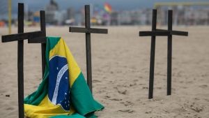 A Brazilian flag hangs on a cross as part of a tribute by the NGO, Rio de Paz, to the late Marcio Antonio do Nascimento Silva and the victims of COVID-19 on Copacabana beach in Rio de Janeiro, Brazil, Wednesday, Oct. 5, 2022. Silva, who died of a heart attack on Oct. 3, lost his 25-year-old son Hugo do Nascimento to the pandemic in April 2020, when he became known for placing crosses on the beach to honor his son and other pandemic victims. (AP Photo/Bruna Prado)
