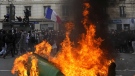 Demonstrators walk past burning garbage cans during a demonstration Tuesday, March 28, 2023 in Paris. (AP Photo/Thibault Camus)