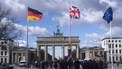 A person raises the Union Jack flag, centre, in front of the Brandenburg Gate at the eve of the visit of King Charles III at the German capital, in Berlin, Tuesday, March 28, 2023. (AP Photo/Markus Schreiber)