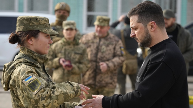 Ukrainian President Volodymyr Zelenskyy presents a medal to a servicewoman in Okhtyrka in the Sumy region of Ukraine, Tuesday March 28, 2023. (AP Photo/Efrem Lukatsky)
