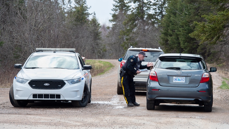 An RCMP officer talks with a local resident before escorting them home at a roadblock in Portapique, N.S. on Wednesday, April 22, 2021. (THE CANADIAN PRESS/Andrew Vaughan)