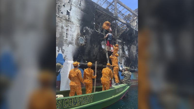 In this handout photo provided by the Philippine Coast Guard (PCG), PCG members check the remains of the MV Lady Mary Joy that caught fire in Basilan, southern Philippines early Thursday, March 30, 2023. (Philippine Coast Guard via AP)
