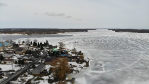 Dividing the United States from Canada, a portion of the frozen St. Lawrence River, flows by the Canadian side of the Akwesane reservation Tuesday, March 15, 2022. (AP Photo/Seth Wenig)