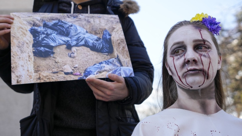 A woman wearing make up to symbolize blood shed, attends a rally to mark the anniversary of the liberation of Bucha, a town outside Kyiv that became a symbol of Russian atrocities against civilians, near the Russian embassy in Belgrade, Serbia, March 31, 2023. (AP Photo/Darko Vojinovic)
