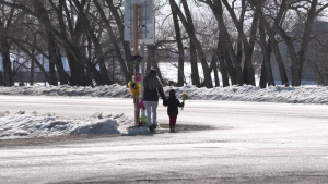 A parent and child bring flowers to a memorial at Highway 5 and Provincial Road 274 near Gilbert Plains, Man. on March 31, 2023. Communities in the area are in mourning after four teenagers were killed following a car crash on March 29, 2023. (Image source: Glenn Pismenny/CTV News Winnipeg)