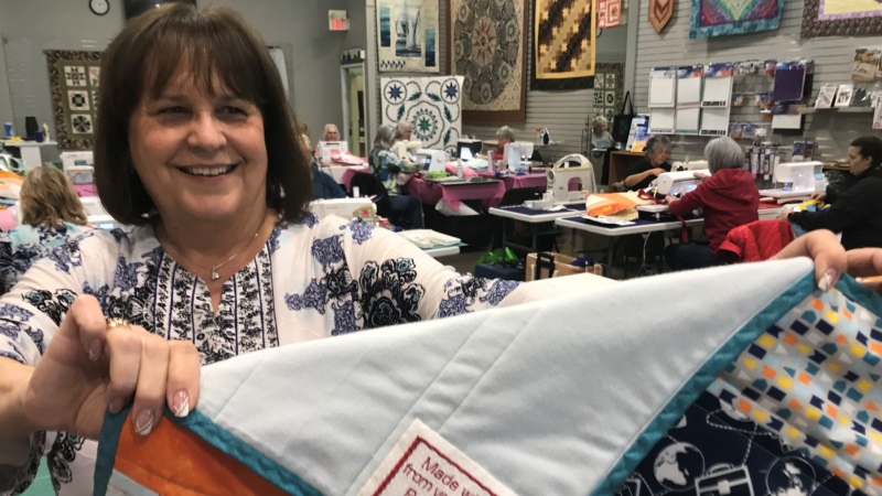 Cheryl Barber holds up one of the 25 quilts made in her shop to be given to Ronald McDonald House Charities. (Michelle Maluske/CTV Windsor)