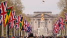 People walk along the Mall where British and Commonwealth countries' flags have been put, ahead of the coronation of King Charles III, in London, on April 27, 2023. (AP Photo/Alberto Pezzali)