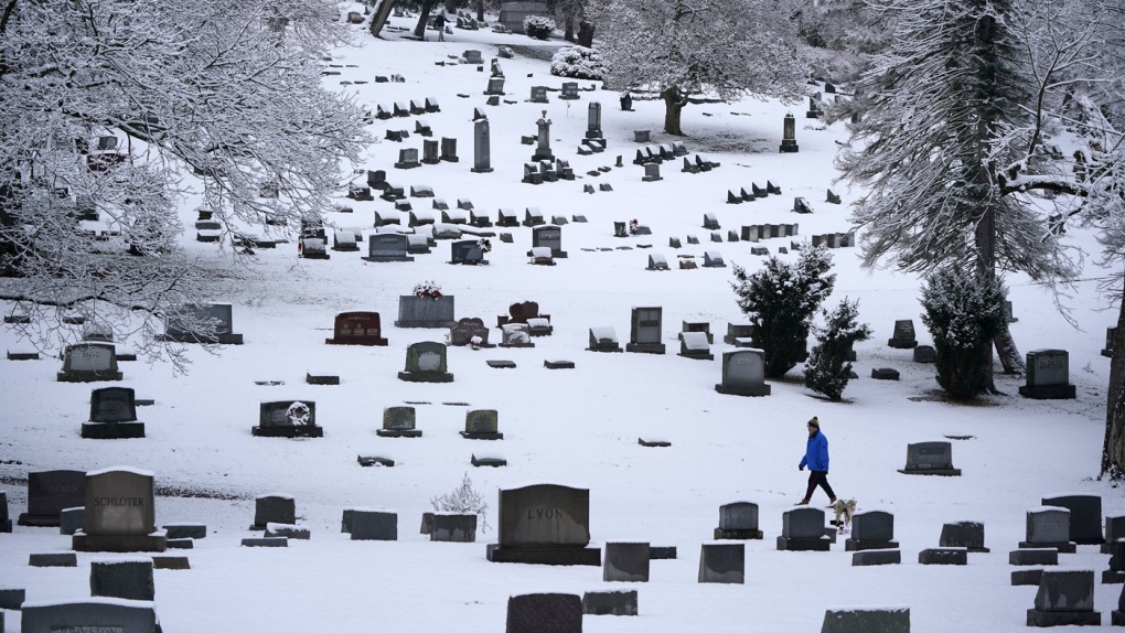 Man walks through snowy Mount Lebanon Cemetery