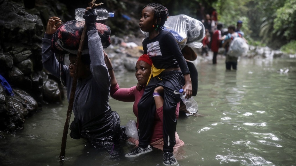 Haitian migrants wade through water 
