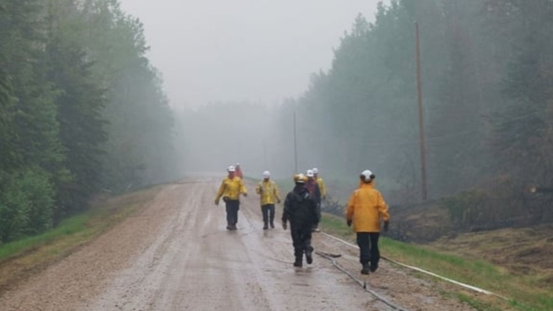Fire crews walk on a wet road near the Sturgeon Lake Complex GCX001 fire in the Grande Prairie Forest Area on May 22, 2023. The area got varying amounts of rain throughout the May long weekend. (Source: Alberta Wildfire)
