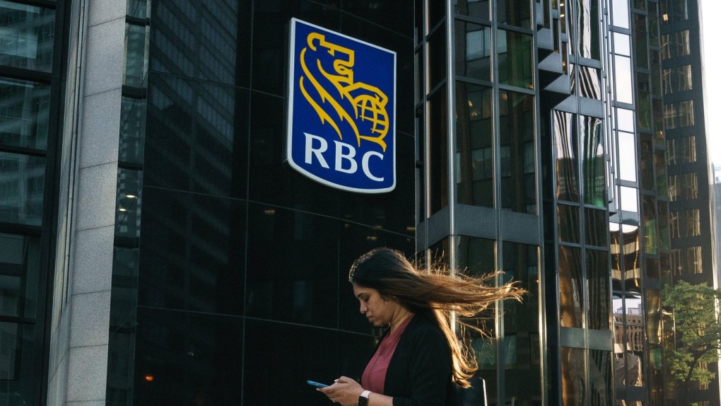 A woman walks past a Royal Bank of Canada sign