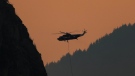A helicopter with a water bucket battling the Flood Falls Trail wildfire picks up water from the Fraser River, in Hope, B.C., Monday, Sept. 12, 2022. THE CANADIAN PRESS/Darryl Dyck