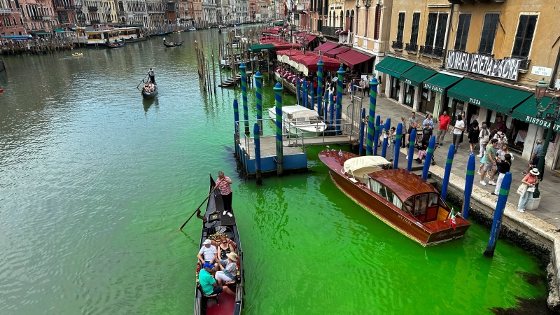A gondola crosses Venice's historical Grand Canal as a patch of phosphorescent green liquid spreads in it, Sunday, May 28, 2023. (AP Photo/Luigi Costantini)