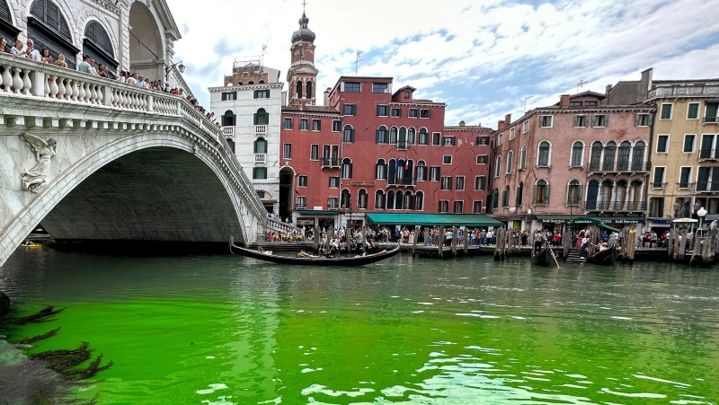 Gondolas navigate by the Rialto Bridge on Venice's historical Grand Canal as a patch of phosphorescent green liquid spreads in it, on May 28. (Luigii Costantini/AP)
