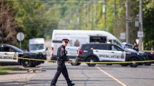 A police officer crosses the street at the scene of a homicide investigation in the area of Jones Road and Barton Street in Hamilton, Ont. Sunday, May 28, 2023. Police say three people are dead following landlord-tenant dispute that became a stand off at a residence late Saturday. THE CANADIAN PRESS/Nick Iwanyshyn 
