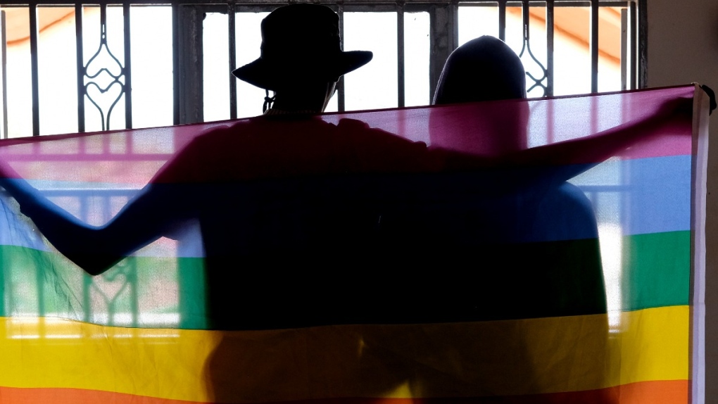 A gay Ugandan couple covered with a pride flag