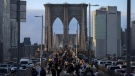 People walk on the Brooklyn Bridge at sunset, Nov. 18, 2022, in New York. metropolis is slowly sinking under the weight of its skyscrapers, homes, asphalt and humanity itself. (AP Photo/Julia Nikhinson, File)