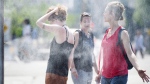 People use misters to cool down during a heatwave in Montreal, on July 2, 2018. Montreal's mayor is unveiling the city's plan to respond to heatwaves after dozens of people died amid high temperatures last summer.THE CANADIAN PRESS/Graham Hughes