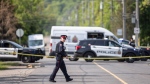 A police officer crosses the street at the scene of a homicide investigation in the area of Jones Road and Barton Street in Hamilton, Ont. Sunday, May 28, 2023. Police say three people are dead following landlord-tenant dispute that became a stand off at a residence late Saturday. THE CANADIAN PRESS/Nick Iwanyshyn