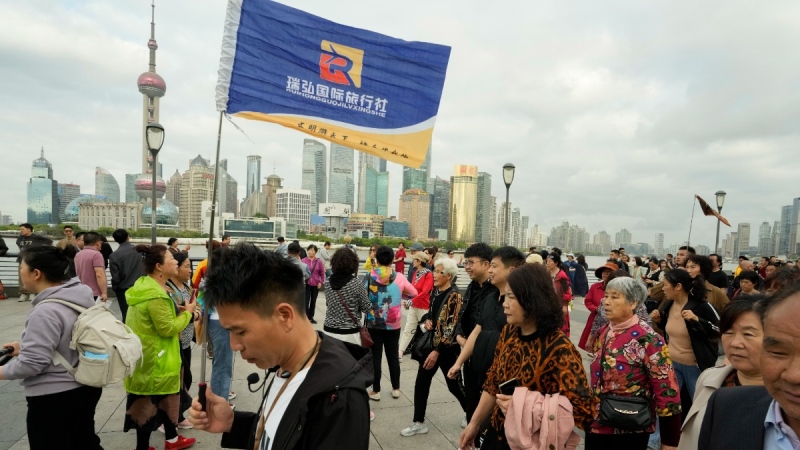 A tour guide holds a flag to lead tourists through the bund in Shanghai, April 20, 2023. (AP Photo/Ng Han Guan)