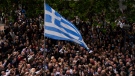 A Greece flag can be seen in the centre of a crowd of people on Monday, May 1, 2023. (AP Photo/Thanassis Stavrakis)