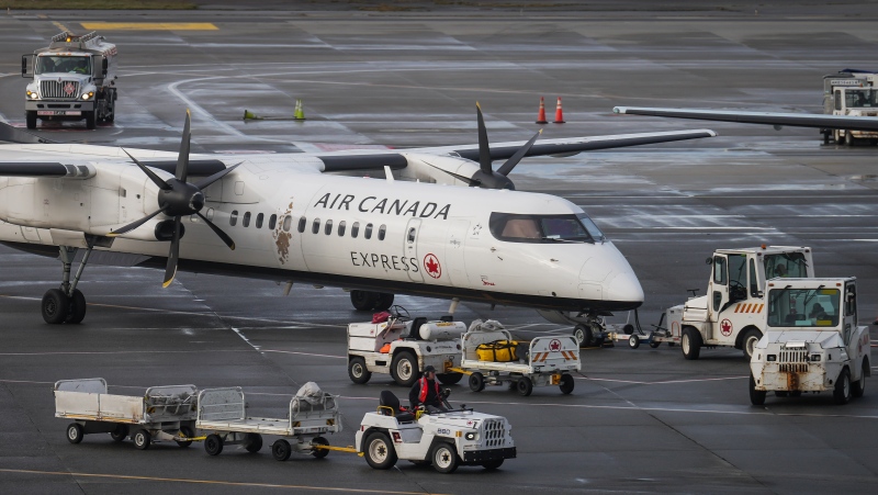 A worker drives past an Air Canada aircraft parked at a gate at Vancouver International Airport after operations returned to normal after last week's snowstorm, in Richmond, B.C., on Monday, December 26, 2022. THE CANADIAN PRESS/Darryl Dyck