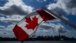 A Canadian flag flies on a boat as gantry cranes at port and the downtown skyline are seen from the harbour, in Vancouver, on Tuesday, April 25, 2023. THE CANADIAN PRESS/Darryl Dyck