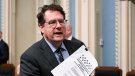 Quebec Education Minister Bernard Drainville holds a copy of a new legislation to reform the education system he tabled, Thursday, May 4, 2023 at the legislature in Quebec City. THE CANADIAN PRESS/Jacques Boissinot