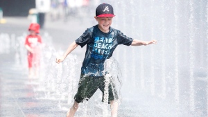 Seven-year-old Samuel Bedard from Quebec City runs through a water fountain as he beats the heat during a heatwave in Montreal, Monday, July 2, 2018. THE CANADIAN PRESS/Graham Hughes