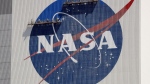 Workers on scaffolding repaint the NASA logo near the top of the Vehicle Assembly Building at the Kennedy Space Center in Cape Canaveral, Fla., May 20, 2020. (AP Photo/John Raoux, File)