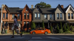 A person walks by a row of houses in Toronto on Tuesday July 12, 2022. THE CANADIAN PRESS/Cole Burston
