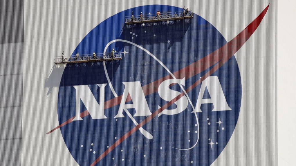 Workers on scaffolding repaint the NASA logo