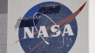 Workers on scaffolding repaint the NASA logo near the top of the Vehicle Assembly Building at the Kennedy Space Center in Cape Canaveral, Fla., May 20, 2020. (AP Photo/John Raoux, File)