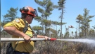 DNRR firefighter Walter Scott sprays the ground while the water bomber flies by to dump a load of water on the fire. (Courtesy: Communications Nova Scotia)