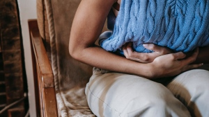 A person suffering from stomach pain is seen in this stock image. (Pexels)