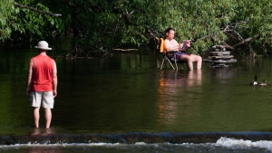 People relax in the Rideau River in Ottawa, on Thursday, June 1, 2023. According to Environment Canada a two-day heat warning has been issued for the region with daytime maximum temperatures reaching 33 degrees Celsius. (Spencer Colby/THE CANADIAN PRESS)