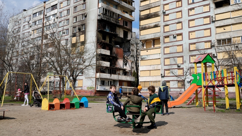 Children play in a playground in front of missile-damaged buildings ahead of a visit by Ukraine's President Volodymyr Zelenskyy Zaporizhzhia, Ukraine, Monday March 27, 2023. (AP Photo/Efrem Lukatsky)