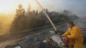 Northfield fire department member Seth Slauenwhite sprays down a flare up along highway 103 near Shelburne, Nova Scotia, N.S. in this Saturday, June 3, 2023 handout photo. THE CANADIAN PRESS/HO-Communications Nova Scotia
