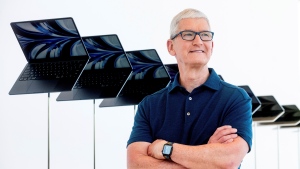 Apple CEO Tim Cook stands in front of a display of new Apple MacBook Air computers with M2 processors, Monday, June 6, 2022, following the keynote presentation of Apple's World Wide Developer Conference on the campus of Apple's headquarters in Cupertino, Calif. (AP Photo/Noah Berger)